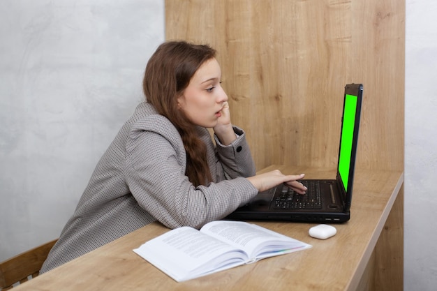 Close up portrait of a young woman looking at laptop doing her work on the distance