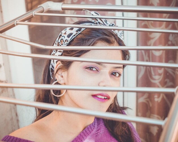 Photo close-up portrait of young woman looking through metal