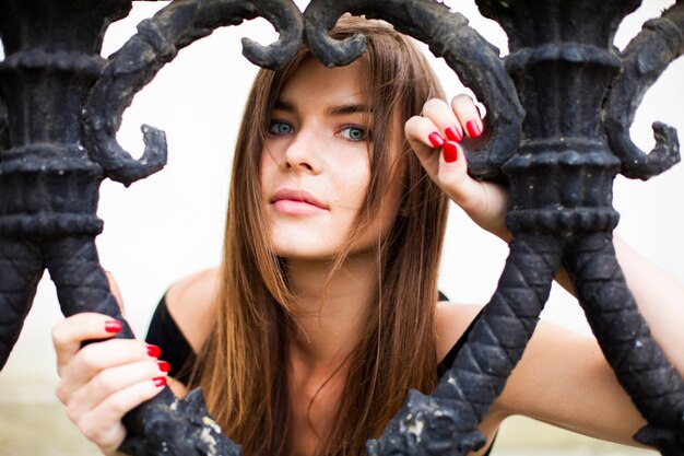 Photo close-up portrait of young woman looking through railing