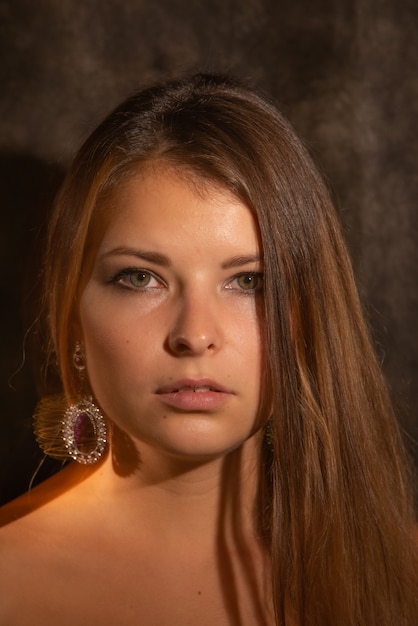 Close-up portrait of young woman in mixed light against dark background