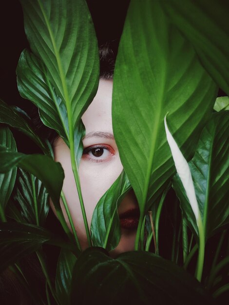 Photo close-up portrait of young woman seen through plants