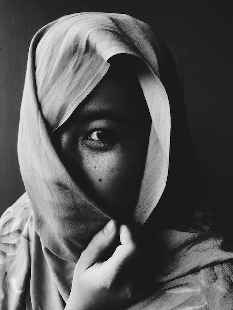 close-up portrait of young woman wearing scarf against black background