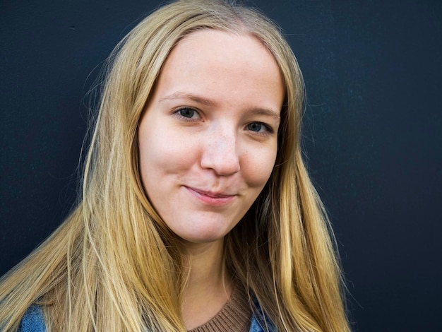 Photo close-up portrait of young woman with blond hair against gray background