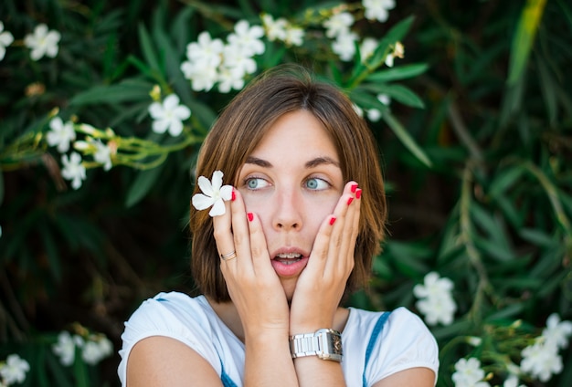 Close up portrait of a young woman with blue eyes with green plants