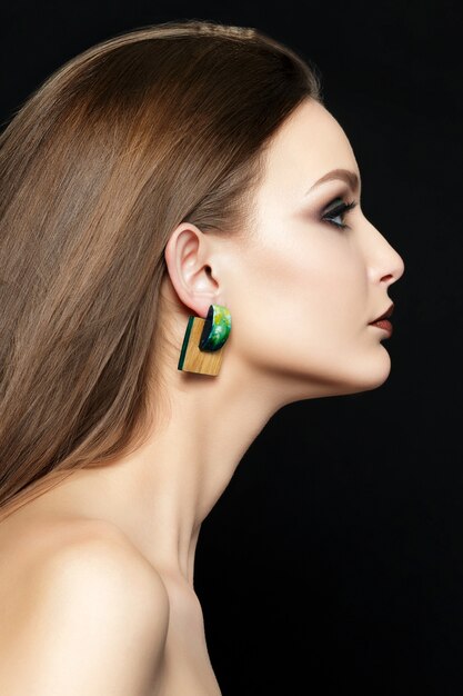 Close up portrait of young woman with brown lips and green smokey eyes. Perfect eyebrows. Modern fashion make up.