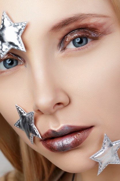 Close up portrait of young woman with creative make up. Liquid glass, metallic glitters and fashion modern smokey eyes.
