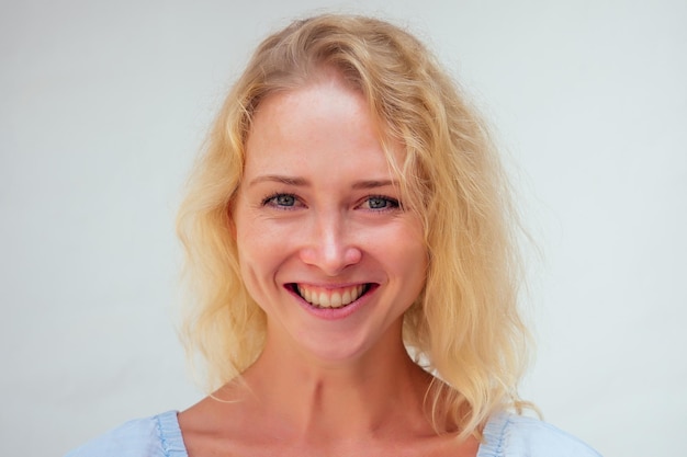 Close up portrait of young woman with long blond damaged dry\
hair split ends and big blue eyes is looking at camera on isolated\
background. unsuccessful hair coloring