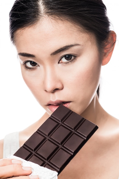 Close-up portrait of young woman with milk chocolate bar