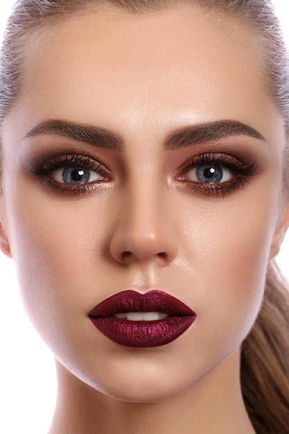 Close up portrait of young woman with wine red lips and bronze smokey eyes. Modern fashion make up.