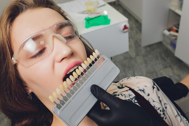 Close up portrait of young women in dentist chair check and select the color of the teeth dentist ma