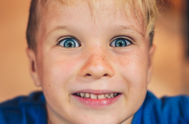 Close-up portret schattige lachende blauwe ogen sproeten blonde jongen uitgesproken artistieke gezichtsuitdrukkingen gebaren intrigerend sluw grappig ondeugend Gelukkige kinderjaren kinderen gedragsproblemen concept