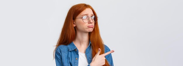 Close-up portret somber en verdrietig pruilend schattig roodharig meisje met mooie blauwe ogen draag een mokkende bril