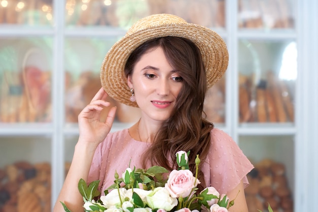 close-up portret van aantrekkelijk jong meisje in jurk en strohoed met een boeket bloemen