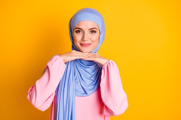 Close-up portret van aantrekkelijke bescheiden vrolijke muslimah dame dragen hijab poseren geïsoleerd over felgele kleur achtergrond