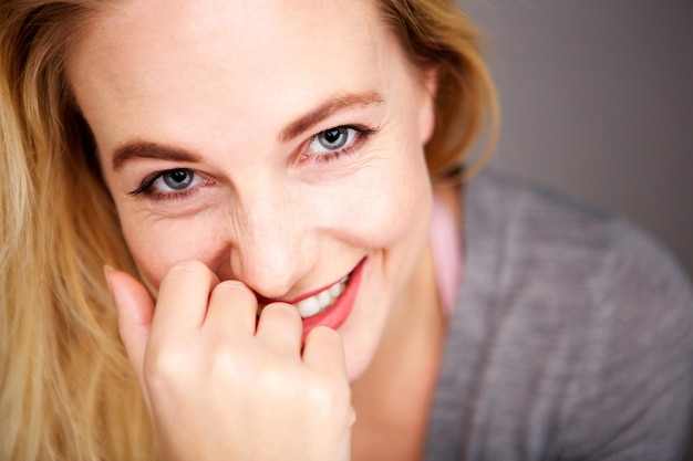 Close-up portret van een gelukkige jonge blonde vrouw die naar de camera kijkt