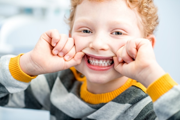 Close-up portret van een gelukkige jonge jongen met een brede glimlach op de tandartspraktijk