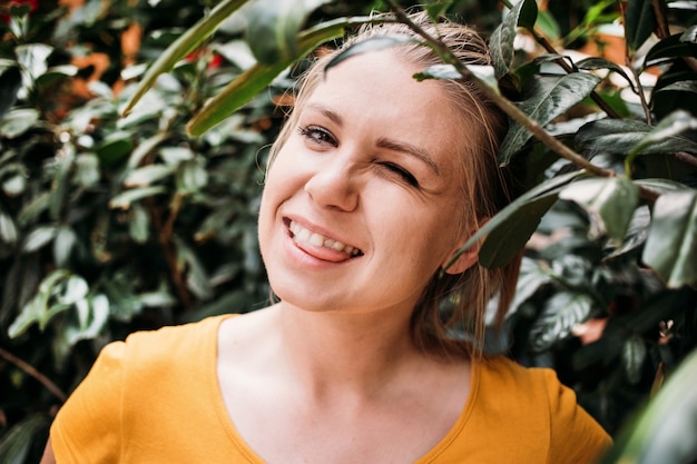 Close-up portret van een gelukkige jonge vrouw in een geel t-shirt die lacht en haar tong laat zien