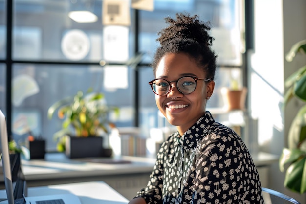 Close-up portret van een jonge Afro-Amerikaanse vrouw in een bril met krullend haar die in een helder kantoor zit met groene potplanten. Mooi glimlachend meisje dat enthousiast werkt of studeert.