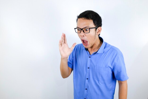 Close-up portret van een jonge Aziatische man schreeuwen luid en boos gezicht met arm op zijn gezicht geïsoleerd over white