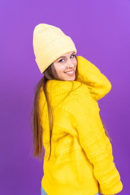 Close-up portret van een jonge blanke vrouw in gele wollen trui geïsoleerd op gele achtergrond glimlachend