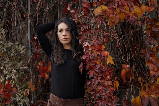 Close-up portret van een jonge brunette vrouw tegen de achtergrond van een bordeaux herfstlandschap