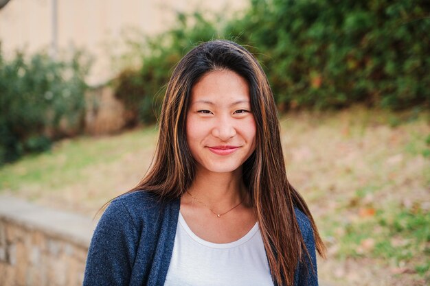 Foto close-up portret van een jonge chinese vrouw die glimlacht en naar de camera kijkt.