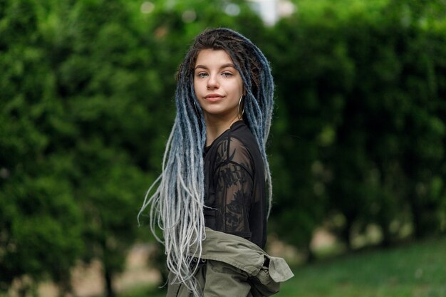 Close-up portret van een jonge mooie lachende vrouw met dreadlocks, vrolijk kijkend naar de camera wandelen in de stad