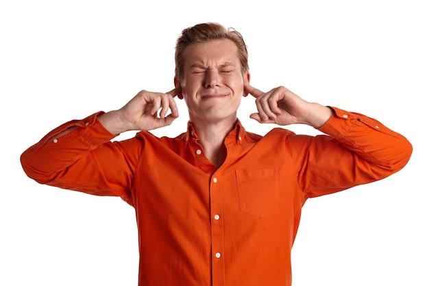 Close-up portret van een jonge slimme gemberman in een stijlvol oranje shirt die doet alsof hij geen geluiden wil horen terwijl hij poseert geïsoleerd op een witte studioachtergrond. Menselijke gezichtsuitdrukkingen. Sinc