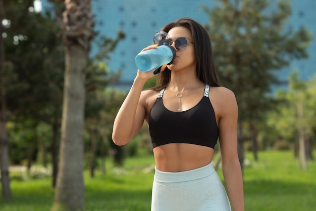Close-up portret van een jonge sport zwarte vrouw drinkwater uit bottle