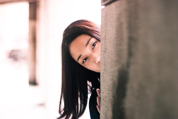 Close-up portret van een jonge vrouw die bij de muur staat