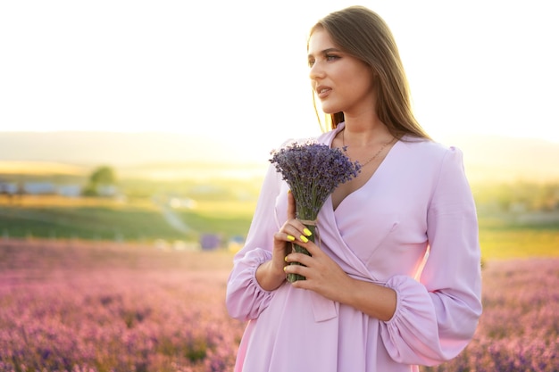 Close-up portret van een jonge vrouw die een boeket lavendel vasthoudt terwijl ze in het lavendelveld staat