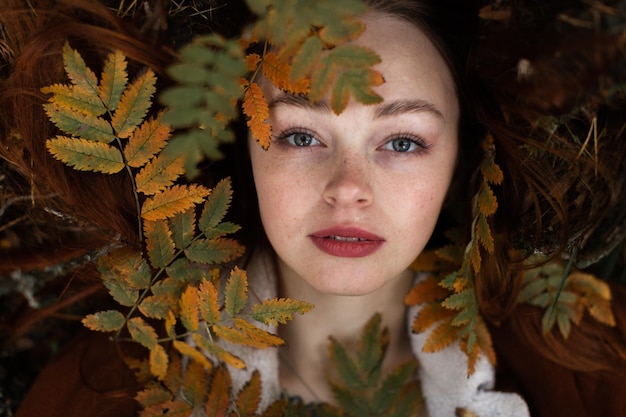 Close-up portret van een jonge vrouw met bladeren in de herfst