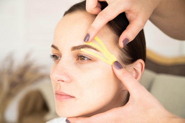 Close-up portret van een jonge vrouw met kinesio-tapes op het gezicht. anti-aging behandeling tegen rimpels.