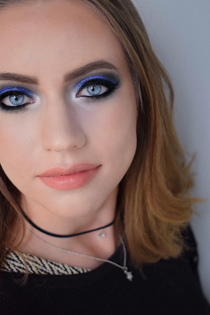 Close-up portret van een jonge vrouw met make-up tegen de muur