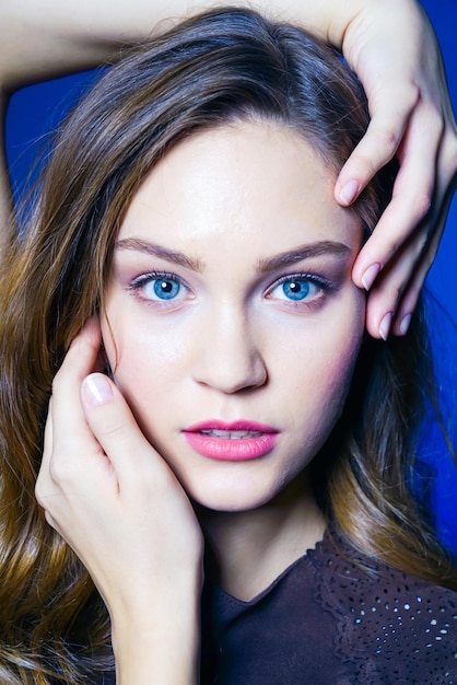 Foto close-up portret van een jonge vrouw tegen een blauwe achtergrond