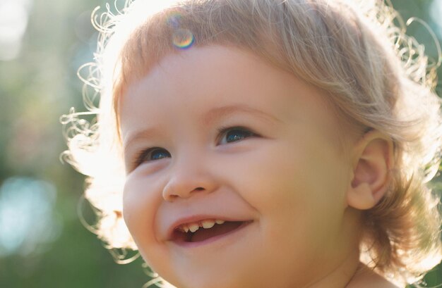 Close-up portret van een kleine blonde babyjongen, grappige kinderen bijgesneden gezicht buiten op zonnige dag kinderen