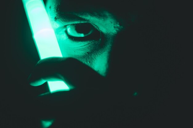 Close-up portret van een man met verlichte verlichting tegen een zwarte achtergrond