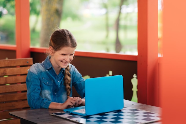 Close-up portret van een meisje achter een laptop, schoolkind werkt op een laptop.