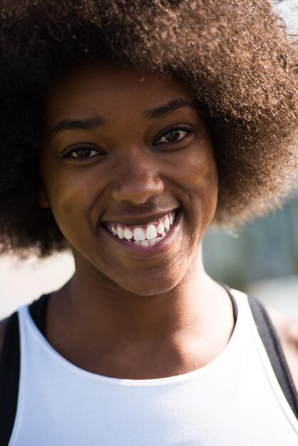 Close-up portret van een mooie jonge Afro-Amerikaanse vrouw die lacht en opkijkt op een mooie zonnige dag