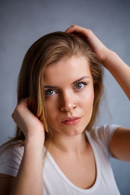 Close-up portret van een mooie jonge vrouw. Emotionele foto van een meisje. Gekleed in een wit t-shirt