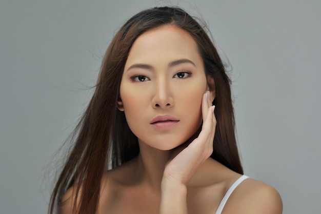 Close-up portret van een mooie jonge vrouw op een grijze achtergrond