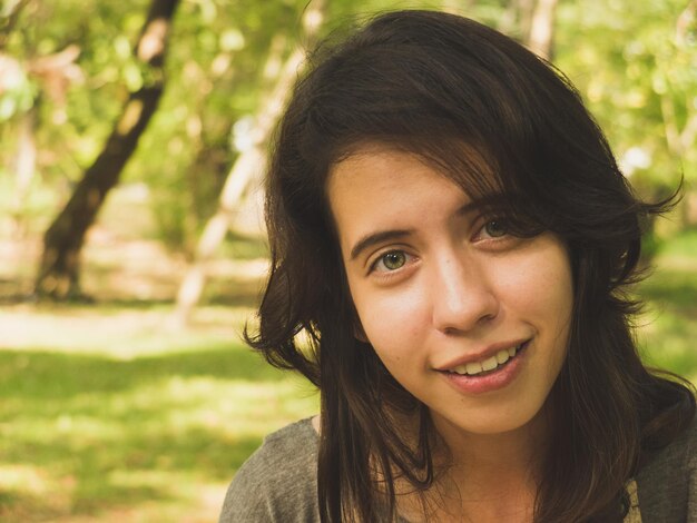 Foto close-up portret van een mooie jonge vrouw tegen bomen