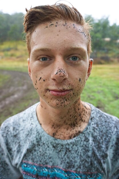 Foto close-up portret van een rommelige tiener jongen die op het veld staat