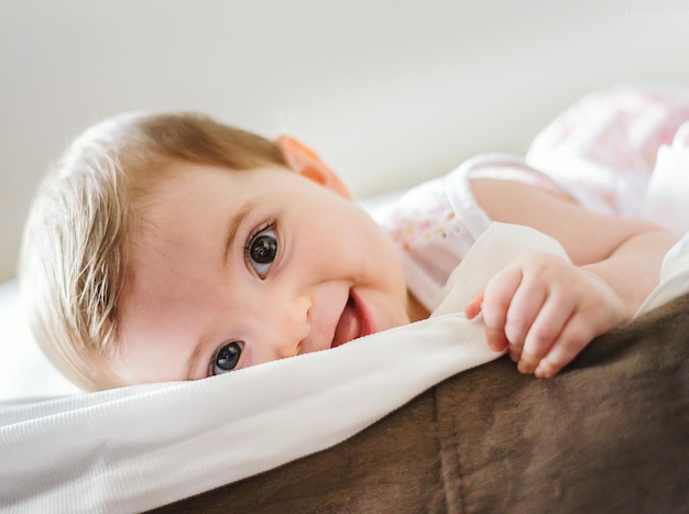 Close-up portret van een schattig baby meisje dat thuis op bed ligt