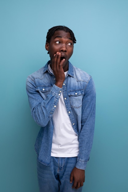 Close-up portret van een verraste jonge Afrikaanse man met dreadlocks in een spijkerjasje