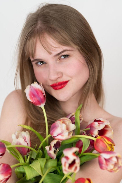 Close-up portret van een vrouw die een boeket kleurrijke tulpen vasthoudt en haar borst bedekt met bloemen