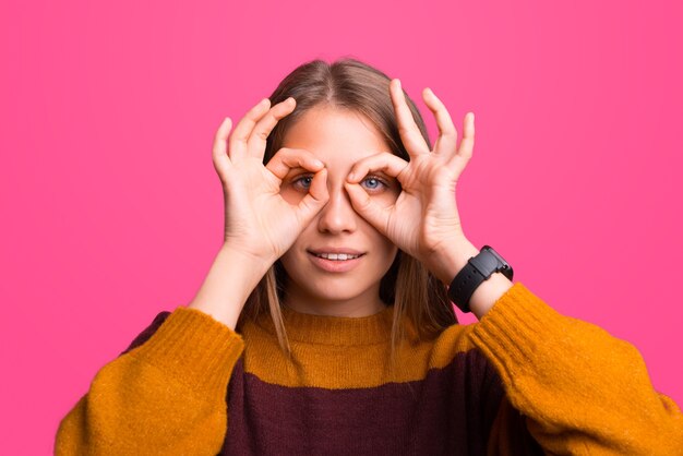 Close-up portret van een vrouw die een verrekijker gebaar maakt.