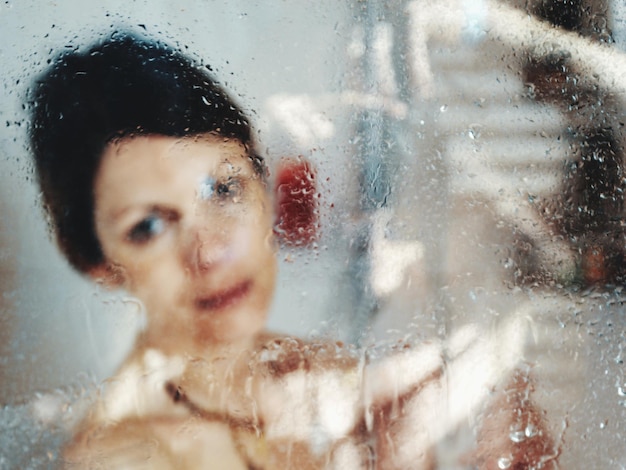 Foto close-up portret van een vrouw gezien door nat glas