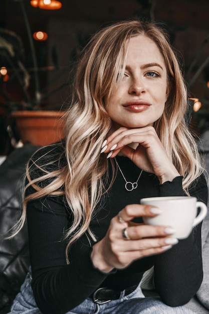 Close-up portret van een vrouw in café. Ze houdt een kopje koffie vast.