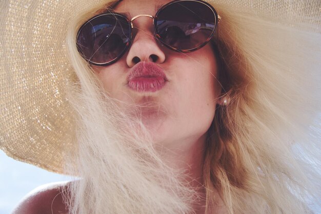 Foto close-up portret van een vrouw met een zonnebril terwijl ze haar lippen plooit